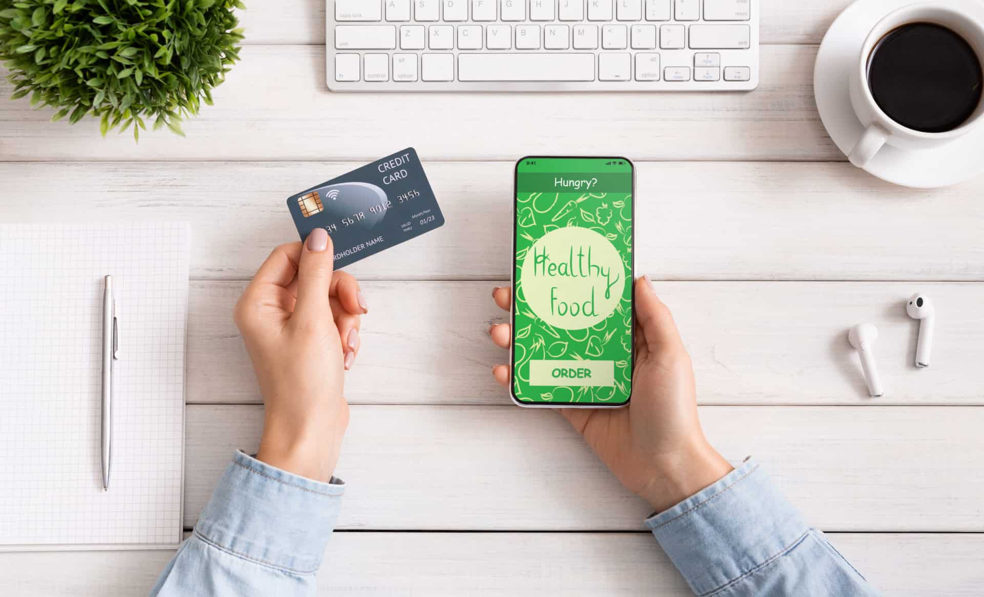 Female hand holding phone with app delivery food on screen Woman using credit card and cellphone with healthy food delivery application on screen