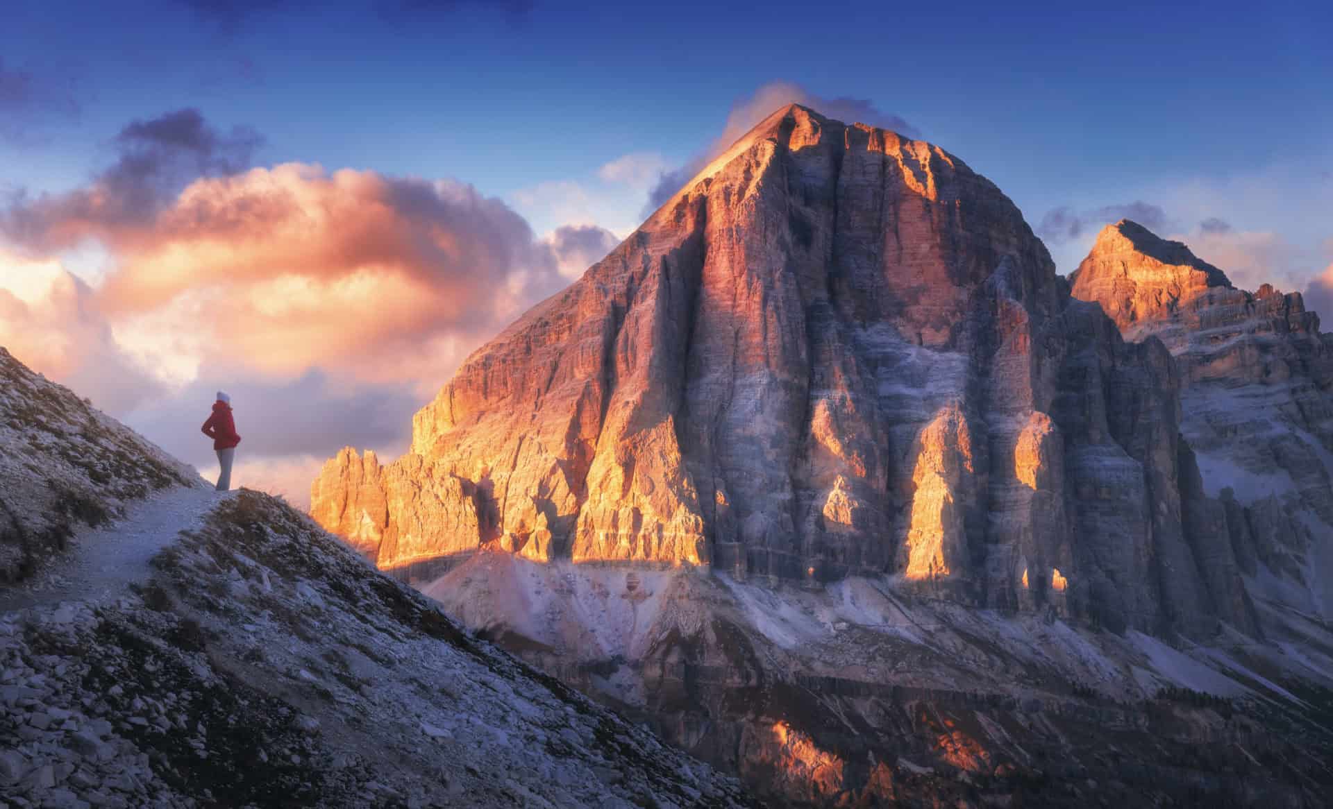 Young woman on the trail against mountain peak at sunset woman hiking in mountains