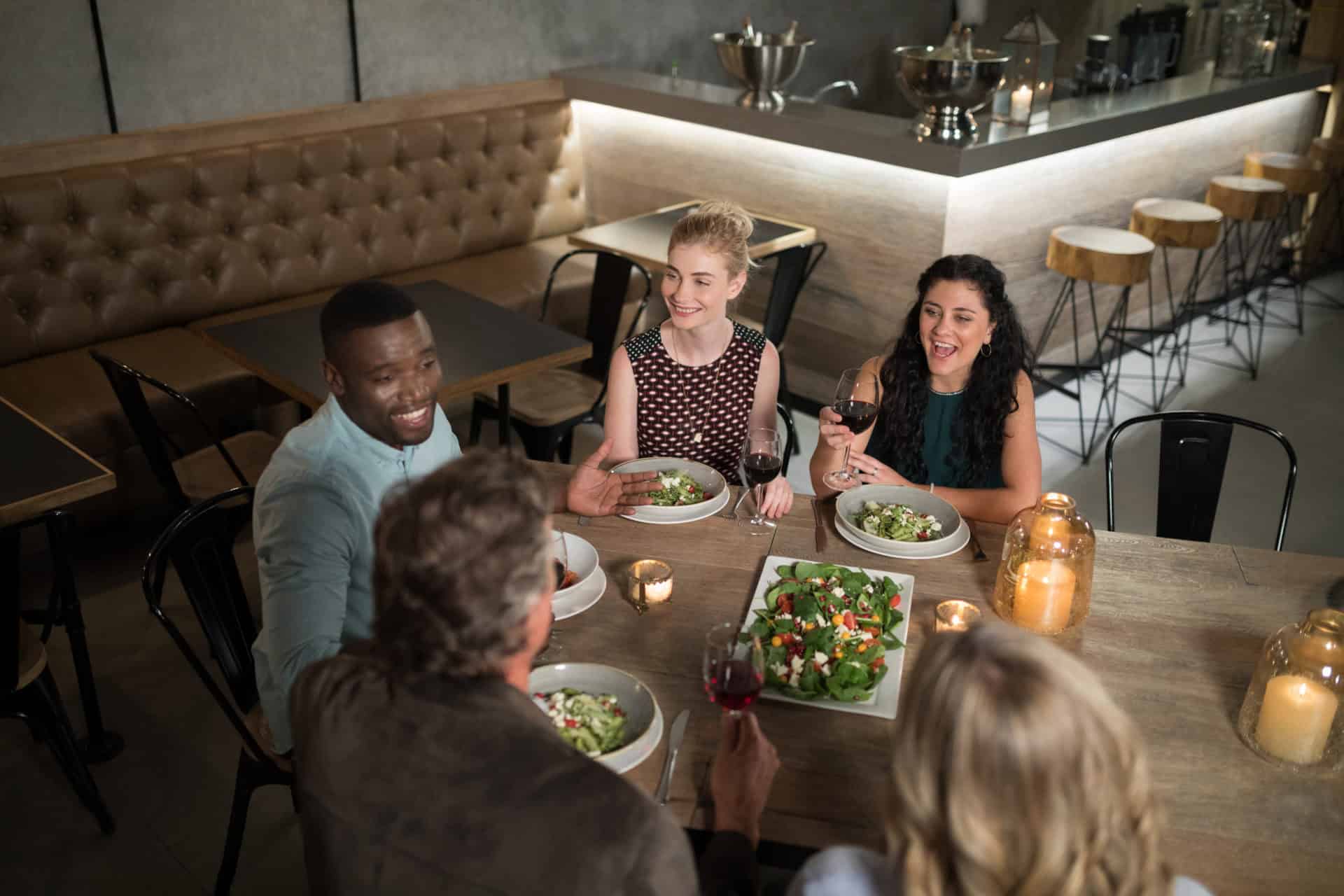 Group of friends interacting with each other while dining Group of friends interacting with each other while dining in restaurant