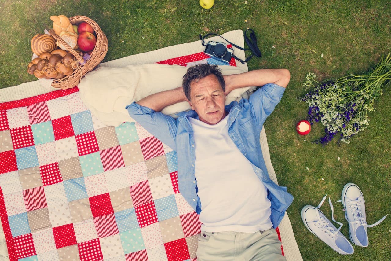 Senior man having a picnic Senior man having a picnic lying on a colorful blanket